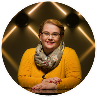 Portrait of Alli Jessing wearing mustard yellow shirt and a scarf and smiling toward the camera.