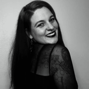 Person smiling over shoulder in black-and-white portrait, showing sheer patterned sleeve.